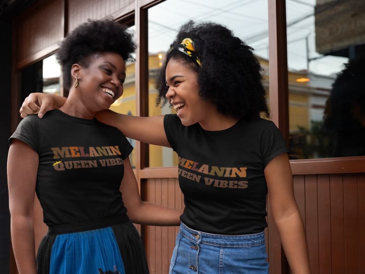 Two Black women laughing wearing matching black history month tshirts