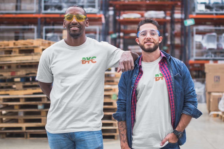  Two men wearing matching white T-shirts with a "DVC" logo stand together in a warehouse.