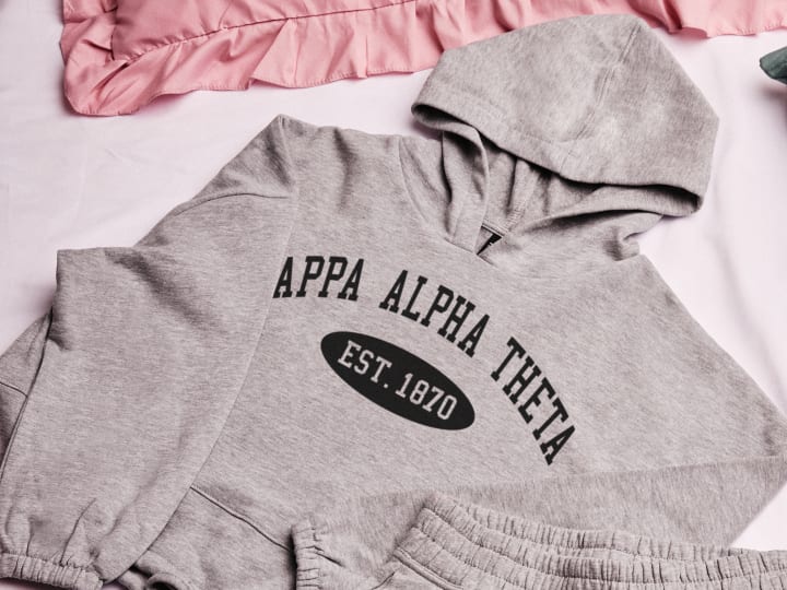 Collection of sorority hoodies with Greek letters and establishment year, shown on a soft fabric background.