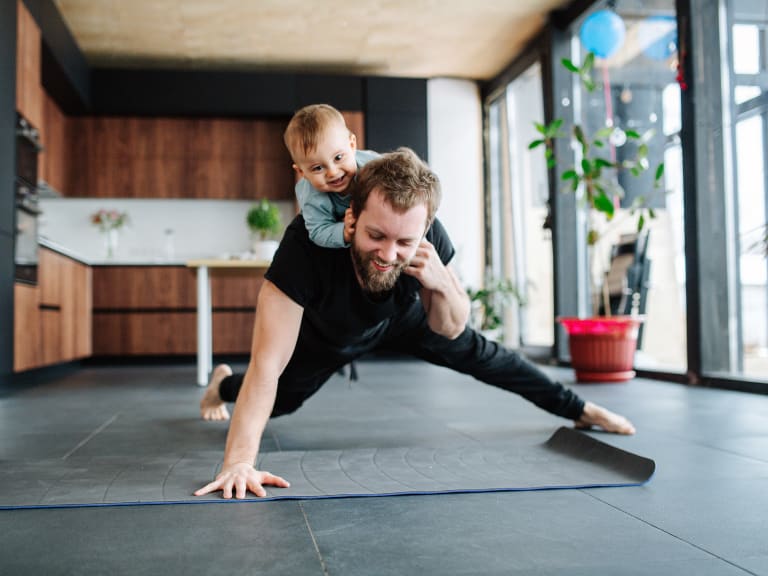 sport zuhause, vater trainiert mit kleinkind auf dem rücken