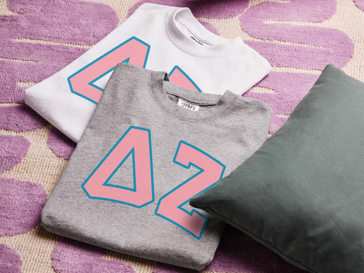 Assorted sorority T-shirts featuring Greek letters and symbols, displayed on a pink and purple background