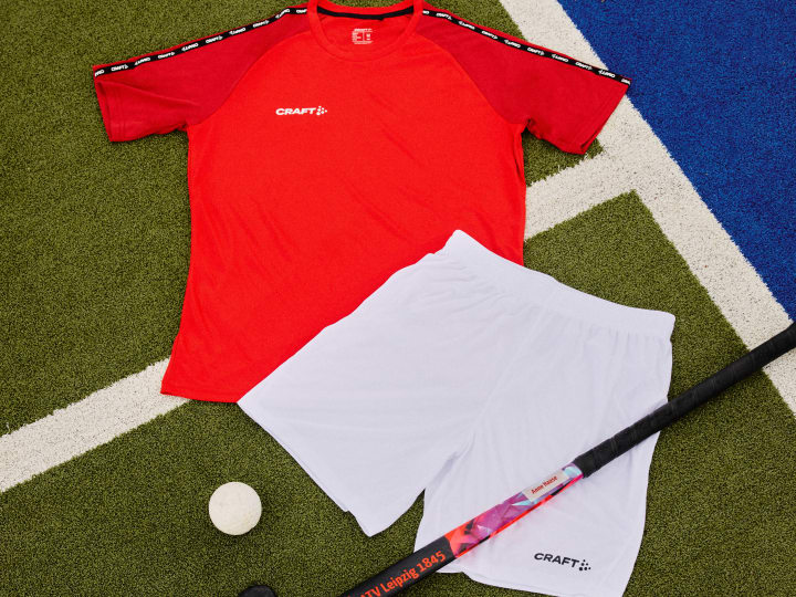 Divisa da gioco rossa e bianca con pantaloncini, mazza e pallina da hockey
