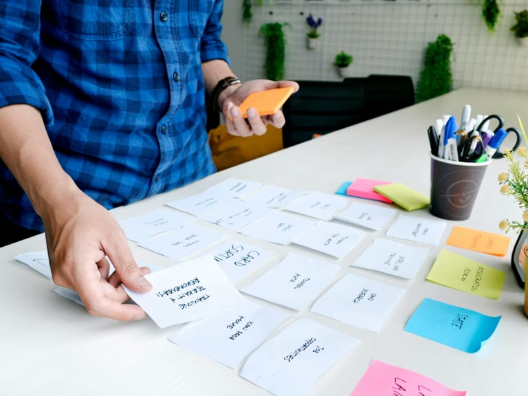 Personne en train de trier et prioriser ses tâches avec des cartes sur un bureau