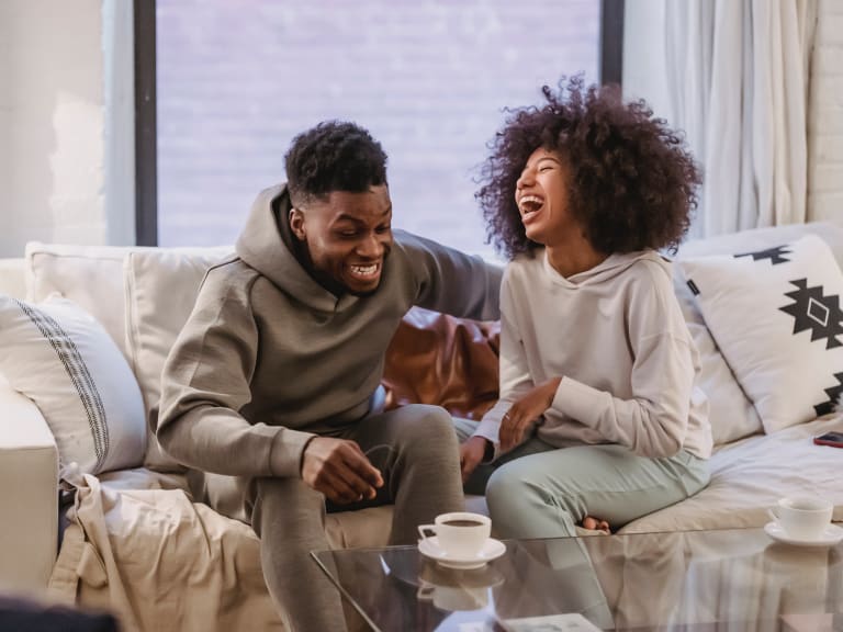 couple laughing wearing hoodies on couch