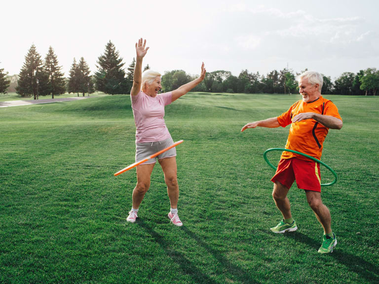 sport für zuhause, älteres ehepaar beim hula hoop draußen