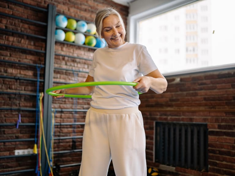 hula hoop übungen für anfänger, ältere dame lächelt beim hula hoop sport