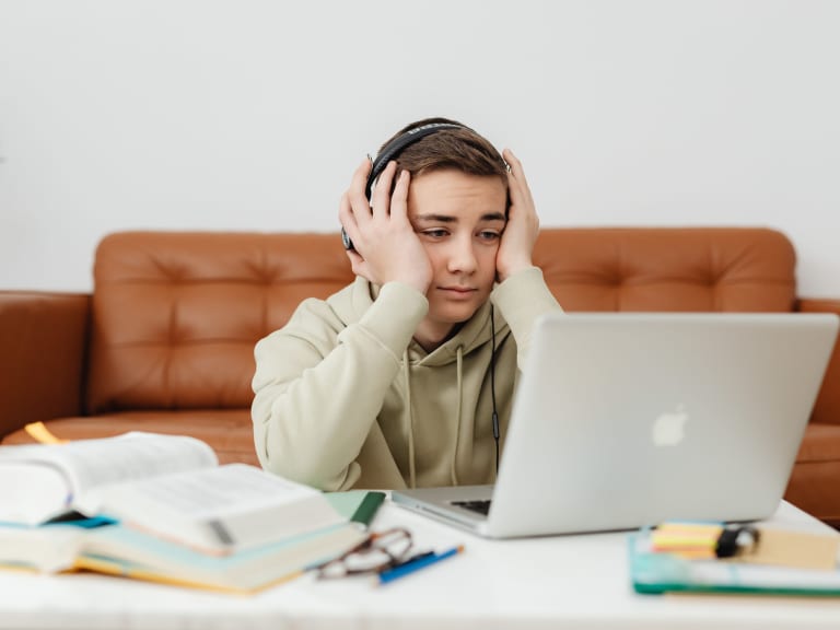 auswendig lernen, verzweifelter schüler mit kopfhörern vor laptop