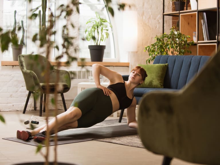 sport für zuhause, frau macht bodyweight training im wohnzimmer