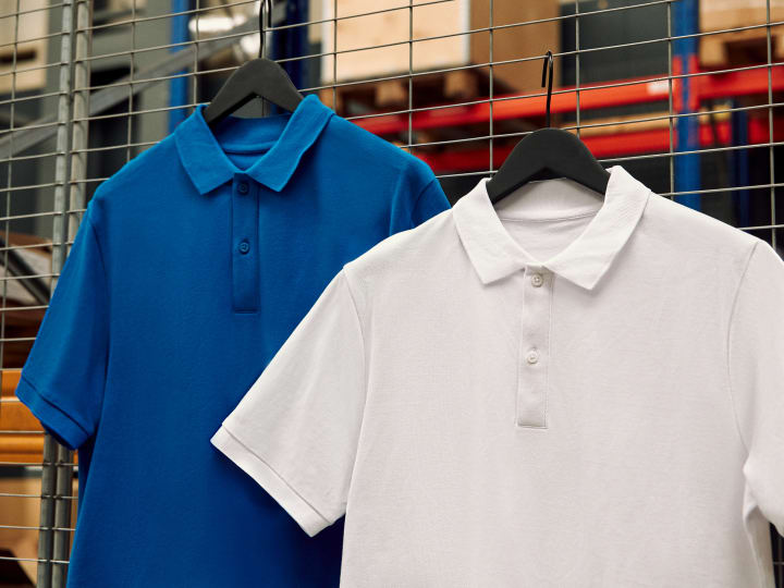Due polo a manica corta, una blu e una bianca, appese ad una rete metallica.