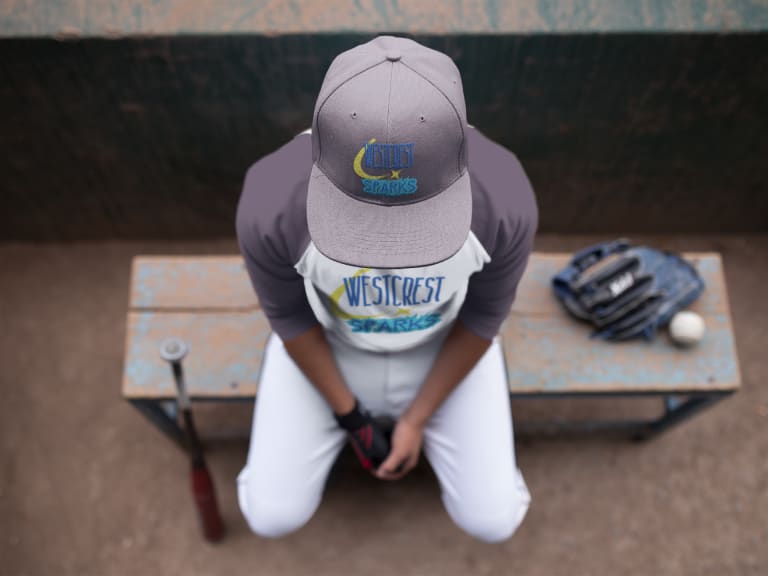 boy wearing baseball uniform sitting on bench