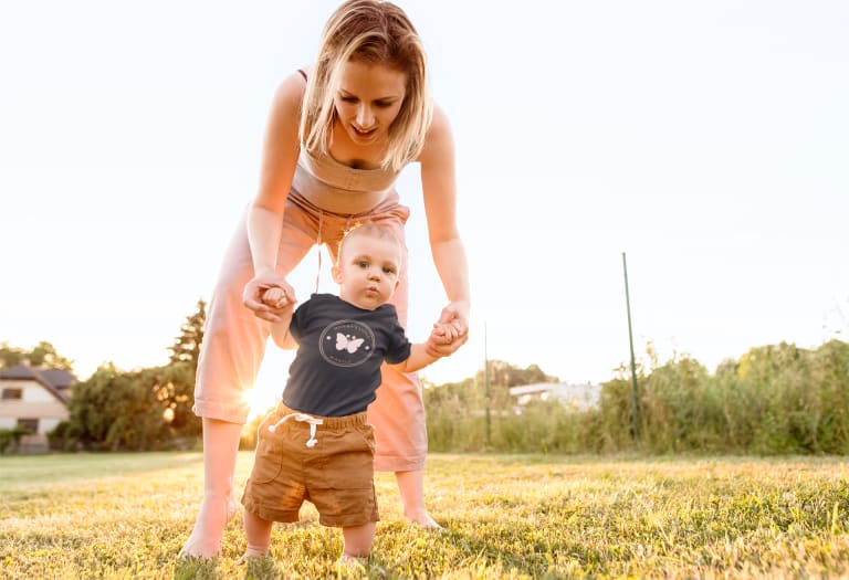 mother helping baby walk in custom printed onesie
