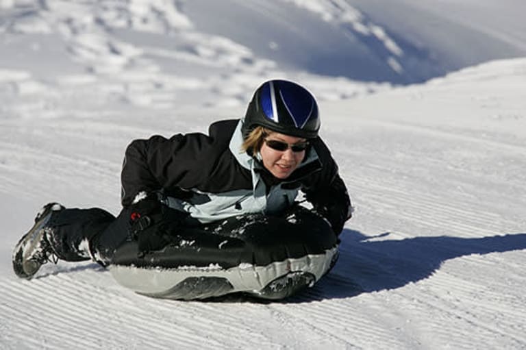 airboarding, frau rodelt auf airboard piste runter