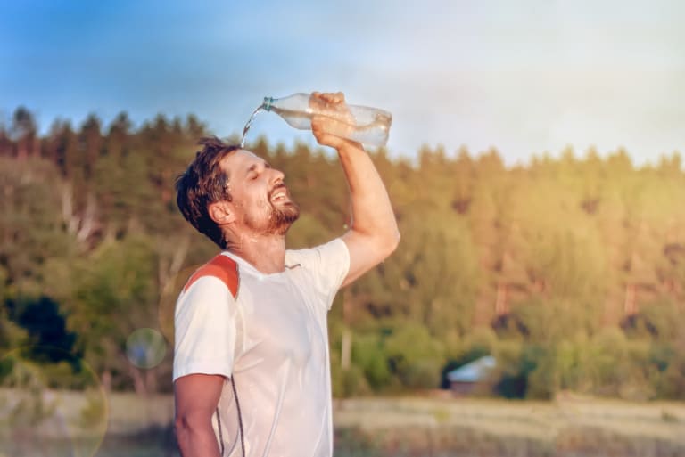 sport bei hitze, jogger erfrischt sich mit wasser
