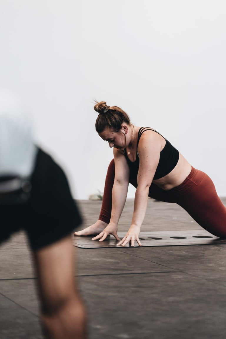 Femme pratiquant le Pilates sur tapis en fente profonde