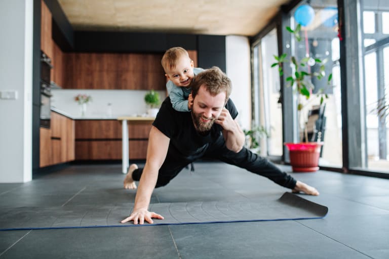 fit im homeoffice, papa macht liegestütze mit sohn auf dem rücken